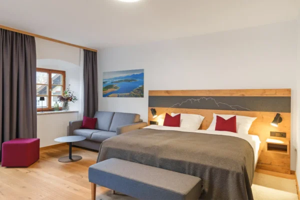 Ihr Ihr Wohlfühlzimmer am Kirchberg. Genießen Sie erholsame Urlaubstage in unserem liebevoll ausgestatteten Zimmer für bis zu 3 Personen oder 2 Erwachsene und 2 Kinder im 1. Obergeschoss. Das komfortable Boxspringbett (auf Wunsch auch getrennt stellbar) sorgt für traumhaften Schlaf, während die Schlafcouch mit hochwertiger Matratze eine gemütliche Zusatzschlafmöglichkeit für eine erwachsene Person oder zwei Kinder bietet. Familienzimmer Dusche/WC, TV, Schlafcouch und Balkon mit Bergblick (30 qm)